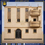 واجهة منزل حديثة بحجر هاشمي كريمي مع تقسيمات منتظمة وديكورات حجرية حول الشبابيك والبلكونات